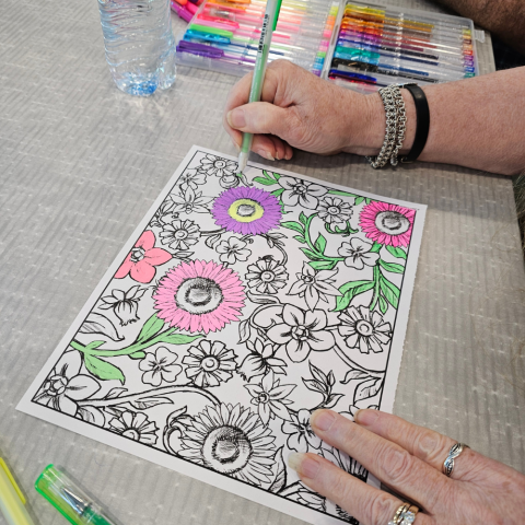 Photo of in-progress coloring page with hands on either side