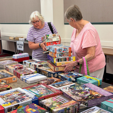 Photo of two ladies looking over a selection of puzzles