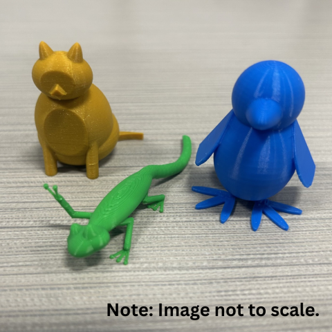 Photo of a gray countertop with three 3D-printed objects, one green lizard, one yellow cat, and one blue penguin