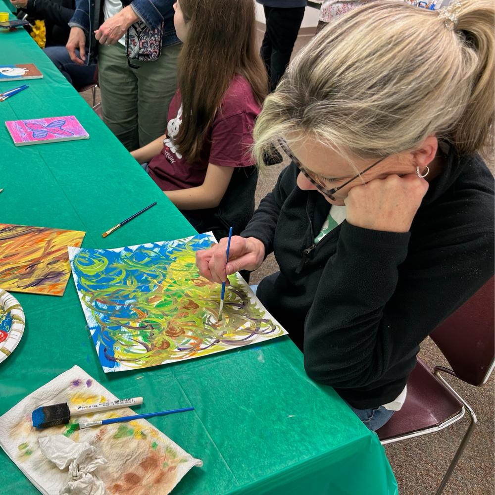 Woman painting a free-form picture at a table with a green tablecloth