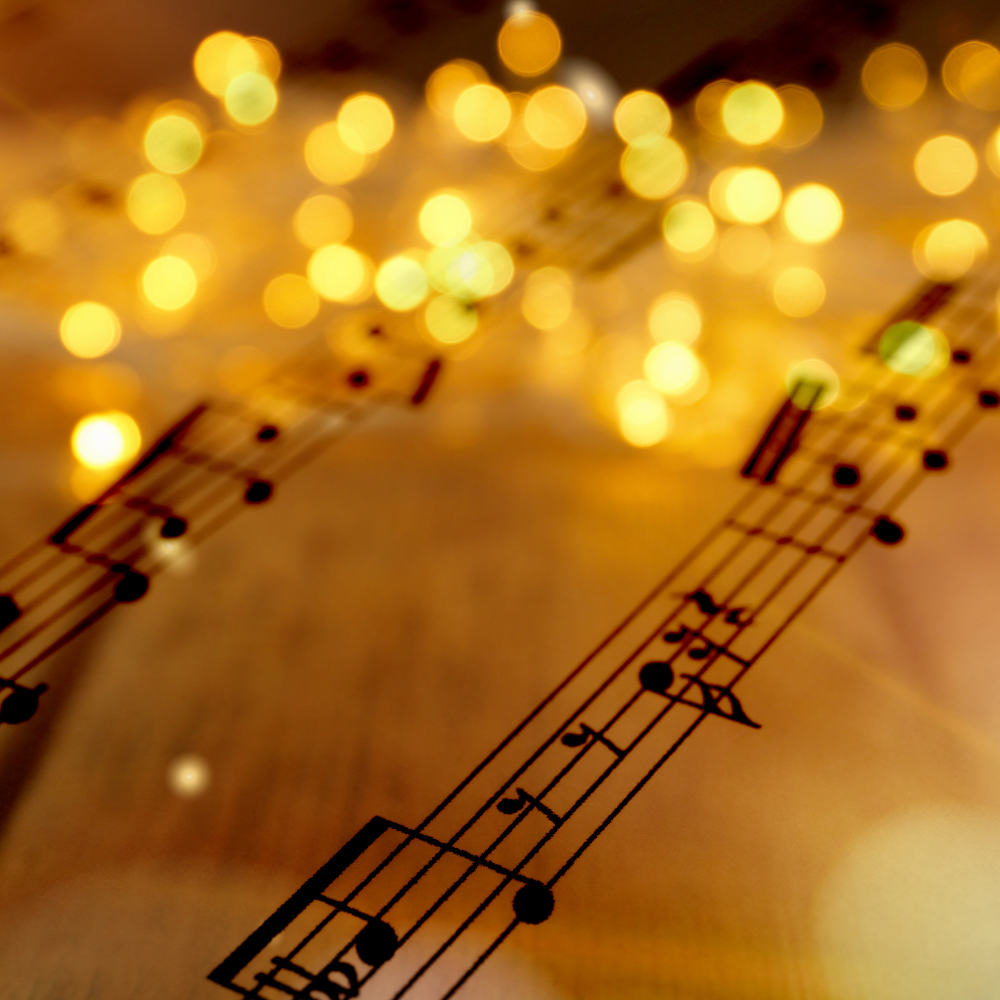 photo of sheet music with white holiday lights near the top