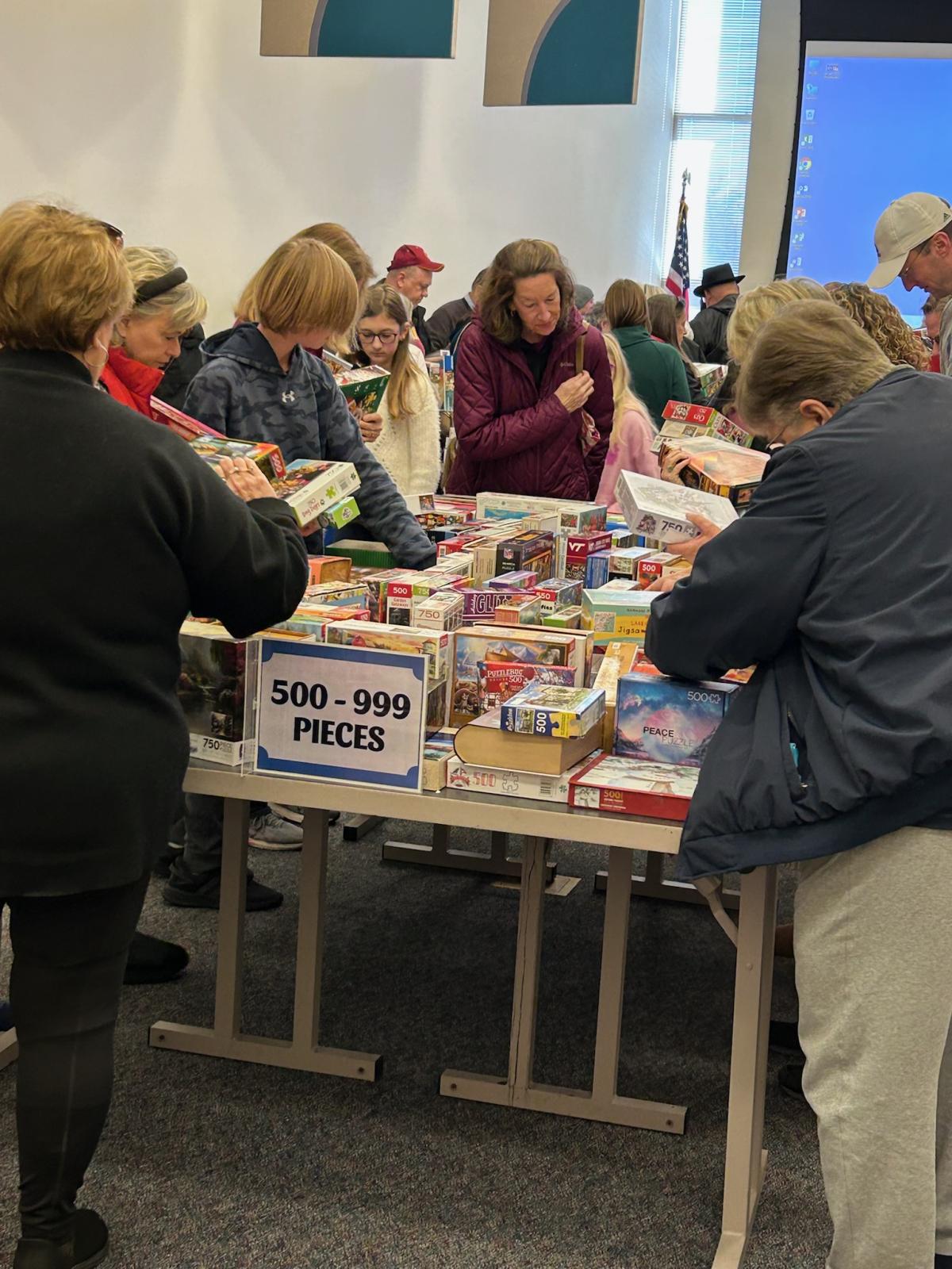 People gathered around a table full of puzzles